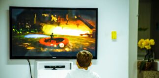 Chłopiec w pokoju gra w grę na dużym ekranie telewizora