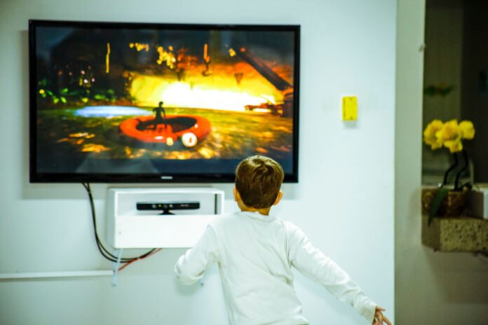 Chłopiec w pokoju gra w grę na dużym ekranie telewizora
