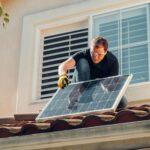 Jak dbać o bezpieczeństwo instalacji elektrycznej w domu z fotowoltaiką i magazynem energii Technik montuje panel fotowoltaiczny na dachu domu